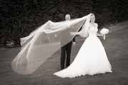 A black and white photo of a bridal veil blowing in breeze.