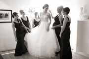 Black and white photo of bridesmaids gather around bride before wedding.