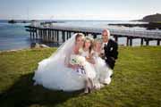 Newlyweds pose with wedding flower girls on Pebble Beach coast.