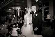 Black and white photo of newlyweds kissing by wedding cake at Beach Club wedding reception.