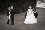 A black and white photo of a bride getting gown bustled.