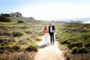 Newlyweds walk on bluff above beach in Big Sur.