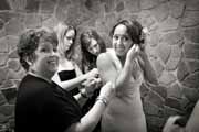 Candid black and white photo of a bride putting on jewelry. 