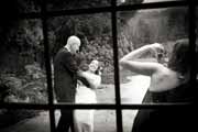 Black and white photo of wedding guest snapping picture of newlyweds.