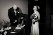 Black and white photo of newlyweds signing wedding license.