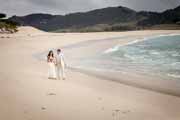 Newlyweds walk on beach after their wedding at Stewarts Cove in Carmel, California.