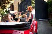 A red VW Bug drving away with bride during wedding ceremony.