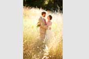 A bride and groom embrace in a golden field.