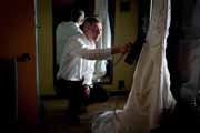 A groom steams wedding gown.