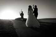 Black and white photo of newlyweds and bagpiper in Pebble Beach.