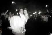 A black and white photo of newlyweds celebrating with sparklers at wedding.