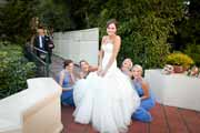 Bridesmaids bustle bride's wedding gown with Pebble Beach bagpiper.