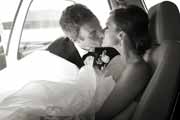 Black and white photo of groom kissing bride in car.