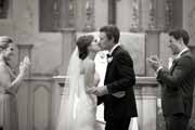 Black and white photo of newlyweds kissing during wedding ceremony.
