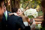 Bride hugs friend while holding white bouquet.