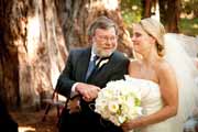 Father gives bride away at redwood forest wedding altar.