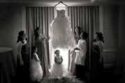 Black and white photo of bridesmaids and bride admiring wedding gown.