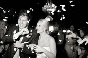 Wedding guests toss flower petals at departing newlyweds.
