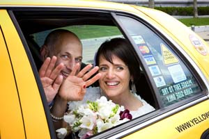 Newlyweds wave from a taxi after their wedding.