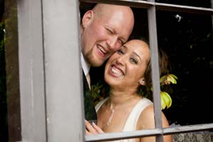 Smiling newlyweds framed in a window of the Brazilian Room.